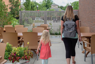 Rear view of mother with daughter walking at outdoor cafe