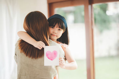 Mother and girl standing at home