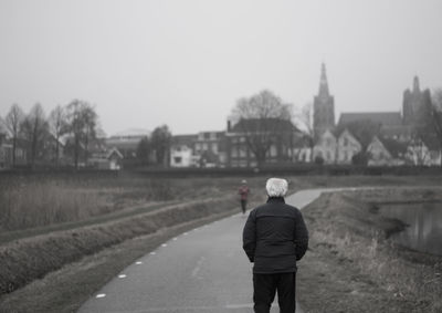 Rear view of man standing against built structure
