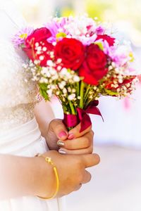 Midsection of bride holding bouquet 