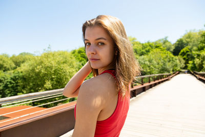 Portrait of woman standing by railing against sky