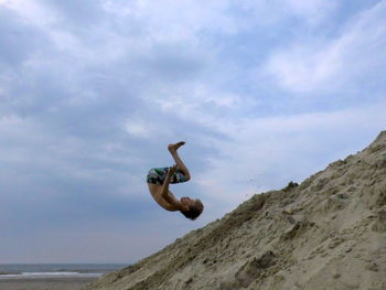 View of boy somersaulting on beach