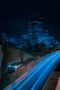 Light trails on road amidst buildings in city at night