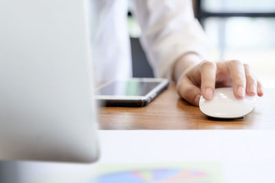 Midsection of man using mobile phone on table