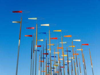 Low angle view of flags against clear blue sky