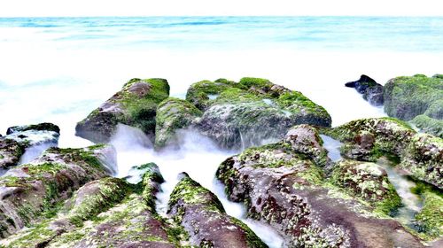 Scenic view of rocks in sea against sky