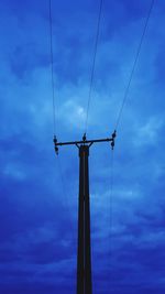 Low angle view of silhouette electricity pylon against sky