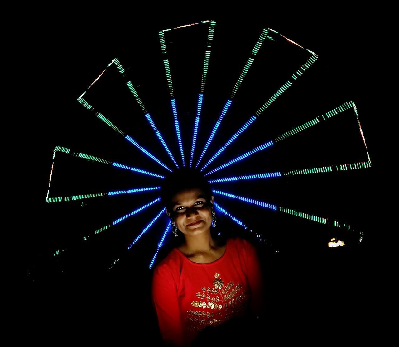 PORTRAIT OF HAPPY YOUNG WOMAN IN ILLUMINATED LIGHTS