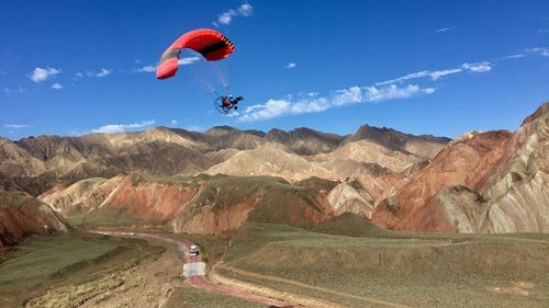 People paragliding over mountain against sky