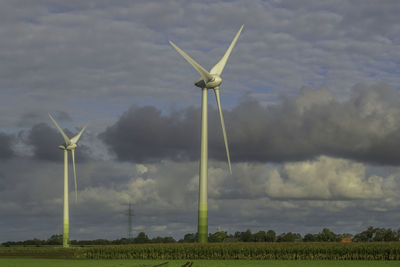 Wind turbines on field against sky