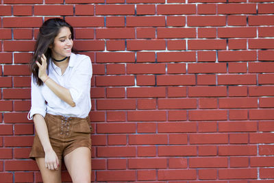 Full length of woman standing against brick wall