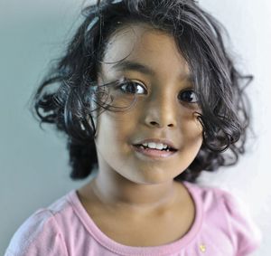Close-up portrait of smiling girl against wall