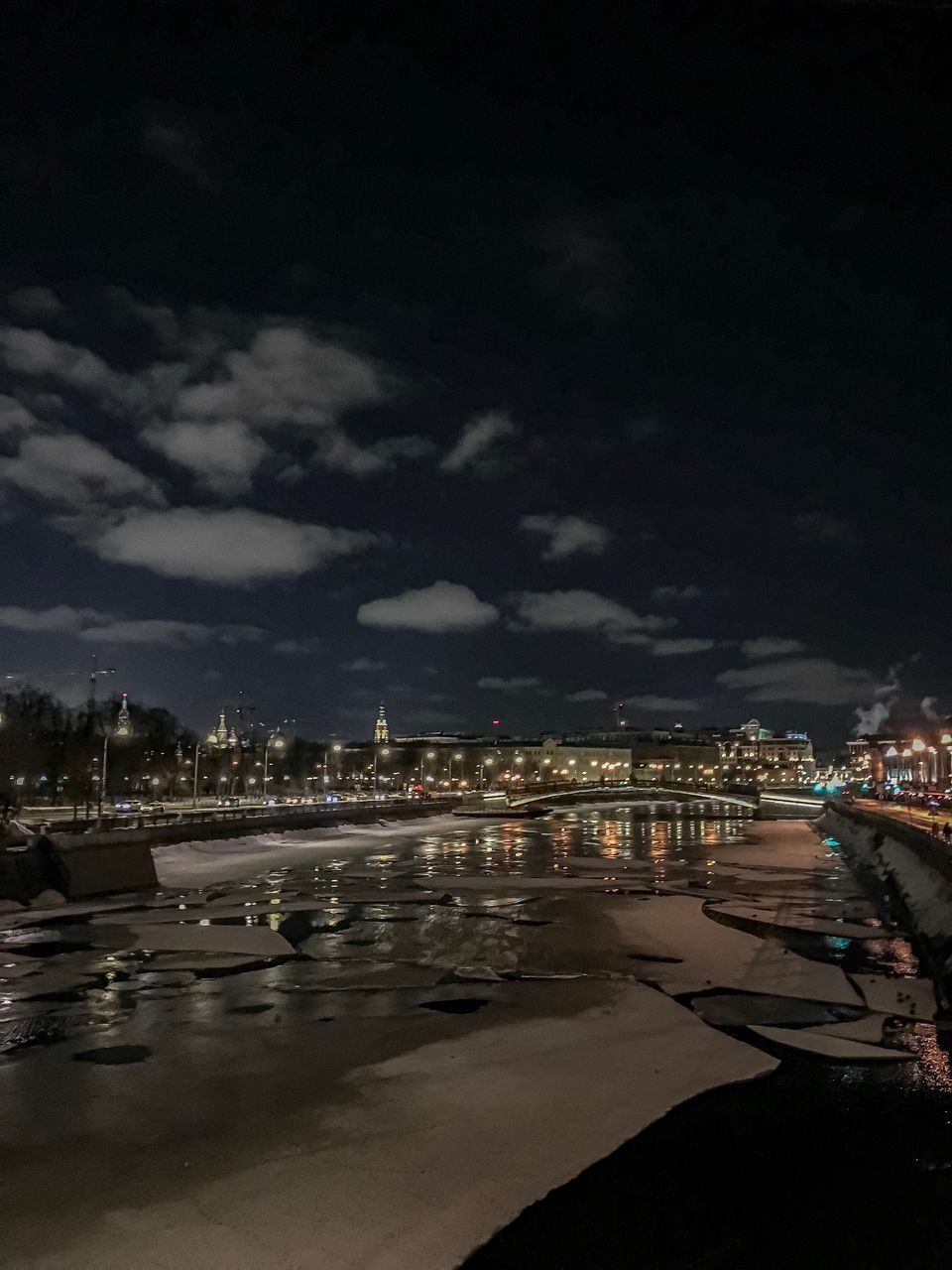 ILLUMINATED CITY BY RIVER AGAINST SKY