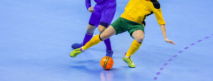 Low section of men playing soccer in court