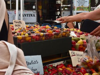 Midsection of woman with fruits at market stall