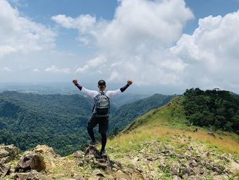 Full length of man with arms raised against sky