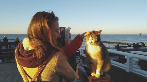 Dog sitting by the sea against sky