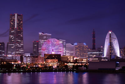 Illuminated modern buildings in city against sky at night