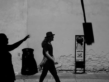 Side view of people standing on street against wall