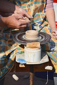 Midsection of woman sitting by pottery wheel