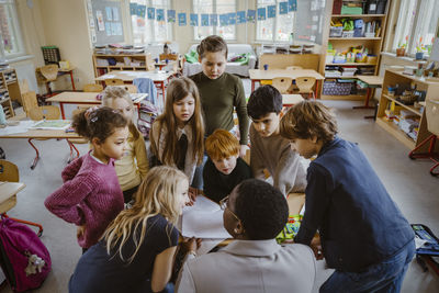 Students looking at teacher helping them in classroom