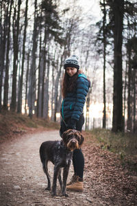 Full length of woman with dog in forest