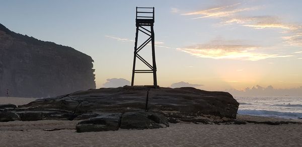 Rock formation on beach against sky during sunset