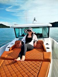 Full length of woman sitting on boat sailing in sea against sky