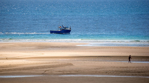 Scenic view of beach and sea against sky, fishing vessel
