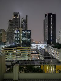 Illuminated buildings in city against sky at night