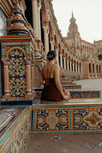 Side view of woman sitting on a building in seville. plaza de espana - spain square