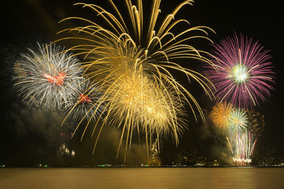 Colorful fireworks celebration and the city night light background with sea view.