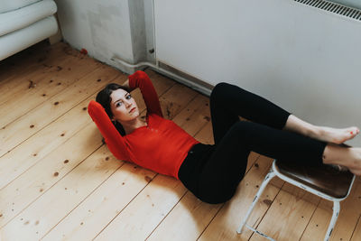 Portrait of young woman lying down on hardwood floor at home