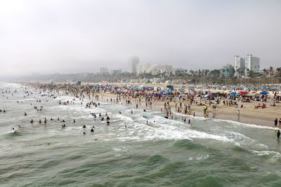 Group of people basking in the sun, sand and waves at santa monica beach, california 