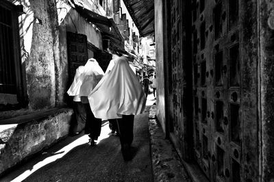 Rear view of people covered with fabric walking on alley