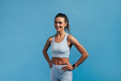 Happy woman standing against blue background