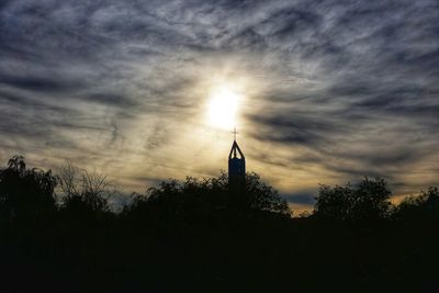 Silhouette of bell tower against cloudy sky