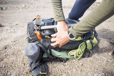 Detail of climber zipping up his backpack in preparation for adventure