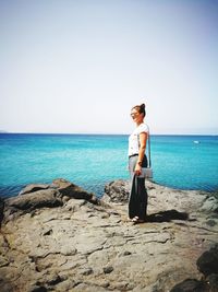 Rear view of woman standing on beach against clear sky