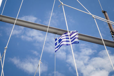 Greek flag waving blue and white in the wind on the masts of a sailing boat against a clear blue sky