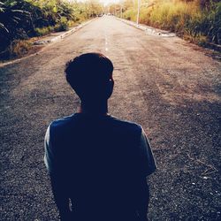 Rear view of man walking on road