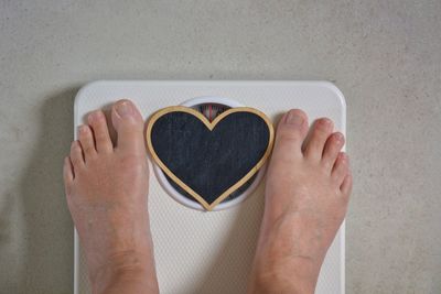 Low section of person with heart shape on weight scale