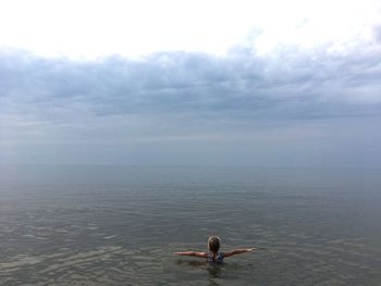Rear view of girl in sea against sky