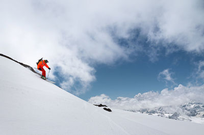 Skier in bright clothes quickly descends the mountain through the snow