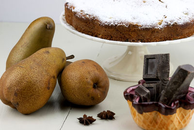 Close-up of pears with chocolate bars and cake on table