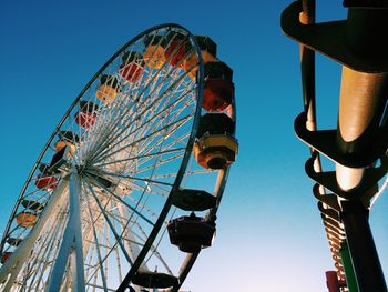 Low angle view of ferris wheel against clear blue sky