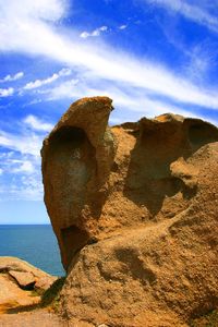 Statue of rock in sea against cloudy sky