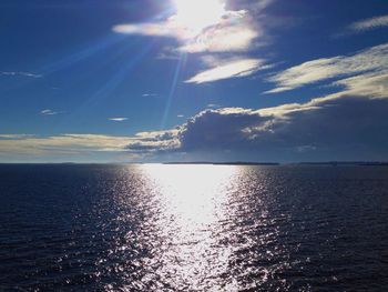 Sun shining through clouds over sea