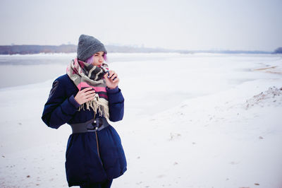 Full length of child photographing on snow covered beach