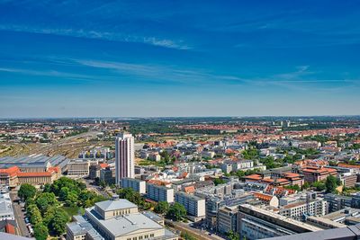 High angle view of city buildings against blue sky